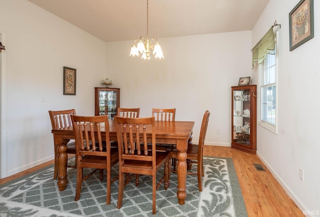 dining area featuring wood-type flooring and an inviting chandelier