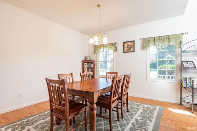 dining space with plenty of natural light, light hardwood / wood-style floors, and an inviting chandelier