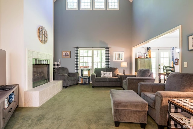 living room with carpet flooring, a fireplace, a towering ceiling, and french doors