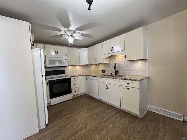 kitchen with light stone countertops, dark hardwood / wood-style flooring, white appliances, sink, and white cabinets