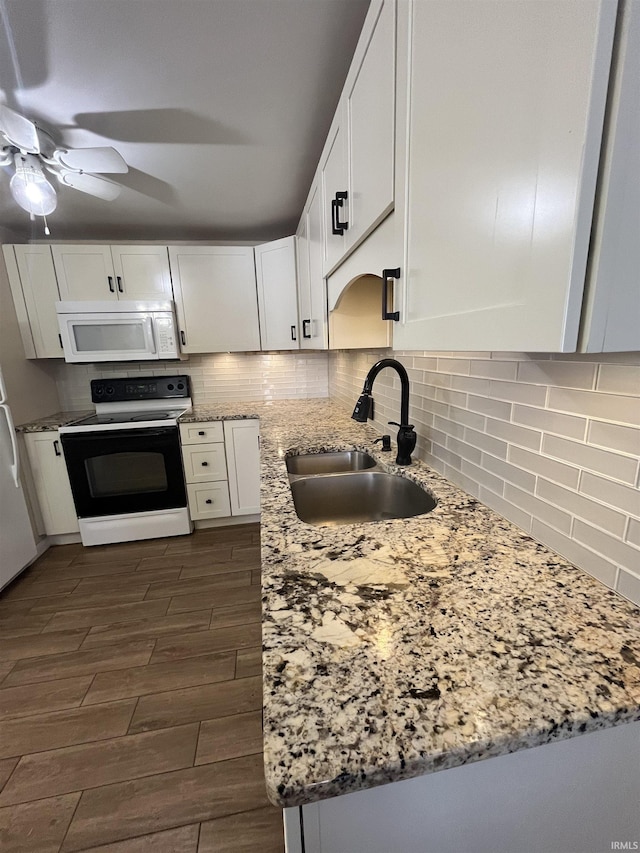 kitchen with white appliances, white cabinets, sink, decorative backsplash, and light stone countertops