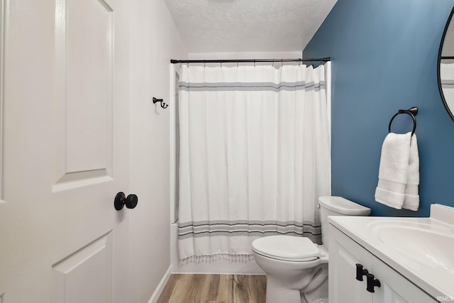 full bathroom with hardwood / wood-style floors, vanity, toilet, shower / bath combo with shower curtain, and a textured ceiling