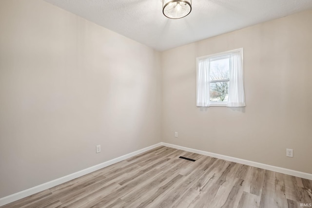 empty room with light hardwood / wood-style floors and a textured ceiling