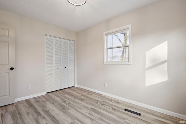 unfurnished bedroom featuring a closet and light wood-type flooring