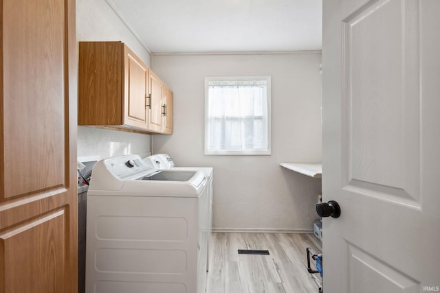 washroom featuring cabinets, light wood-type flooring, separate washer and dryer, and crown molding