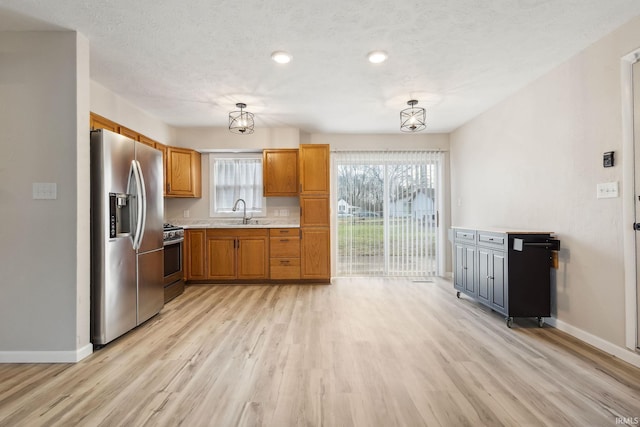 kitchen with stainless steel appliances, sink, a chandelier, light hardwood / wood-style floors, and hanging light fixtures