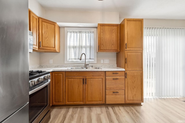 kitchen featuring stainless steel appliances, light hardwood / wood-style floors, and sink