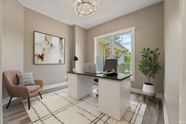 office with light hardwood / wood-style flooring and a textured ceiling