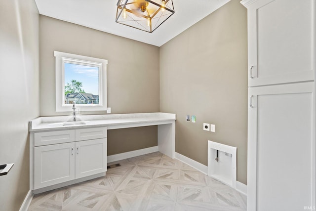 clothes washing area with hookup for an electric dryer, cabinets, sink, and light parquet flooring