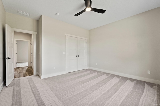 unfurnished bedroom with ceiling fan, light carpet, and a closet