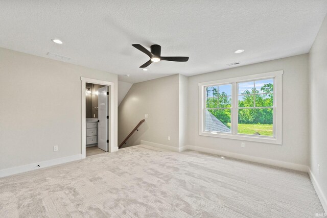 empty room with vaulted ceiling, ceiling fan, light colored carpet, and a textured ceiling