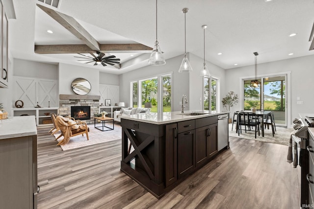 kitchen with dark brown cabinetry, sink, decorative light fixtures, and a stone fireplace