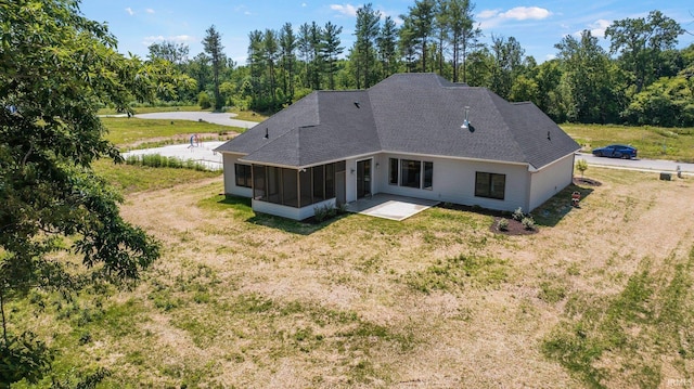 rear view of house with a sunroom, a patio, and a lawn