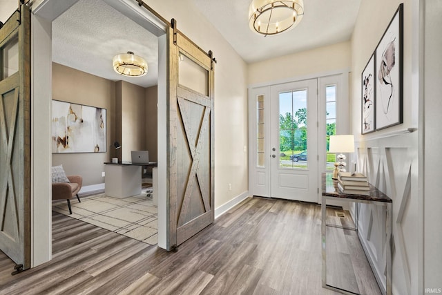 entrance foyer featuring a textured ceiling, a barn door, and hardwood / wood-style flooring