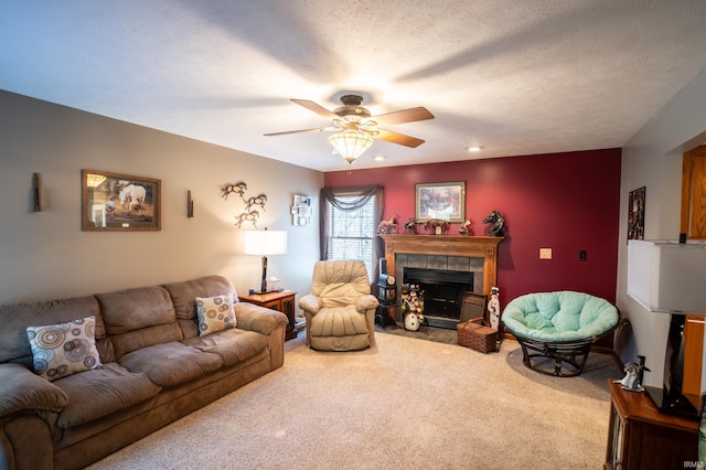 living room featuring carpet flooring, a tile fireplace, ceiling fan, and a textured ceiling