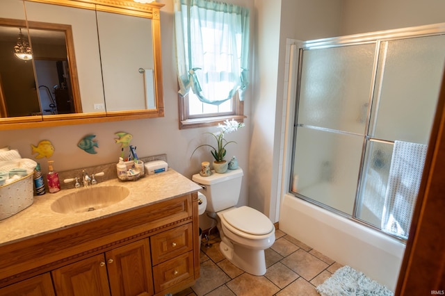 full bathroom with tile patterned flooring, vanity, bath / shower combo with glass door, and toilet