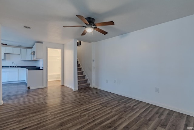 unfurnished living room featuring ceiling fan, sink, and dark hardwood / wood-style floors