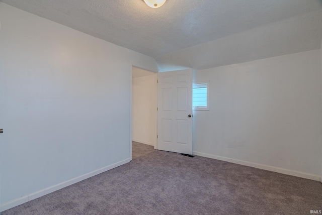 empty room with carpet flooring, lofted ceiling, and a textured ceiling