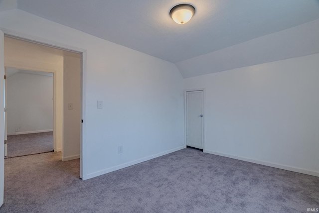 spare room featuring light colored carpet and lofted ceiling