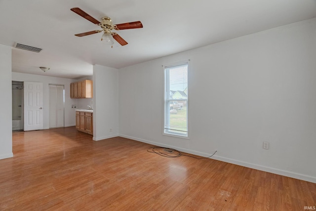 unfurnished living room with ceiling fan, sink, and light wood-type flooring