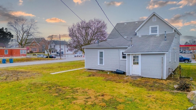 back house at dusk with a lawn