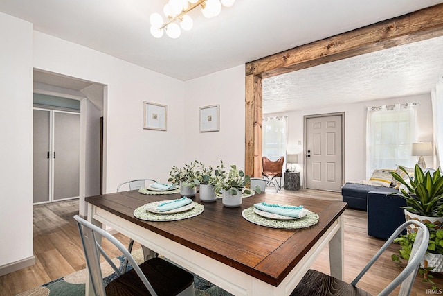 dining space with an inviting chandelier, a textured ceiling, and hardwood / wood-style flooring