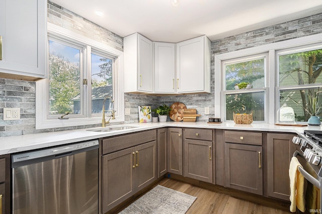 kitchen featuring dishwasher, white cabinets, sink, light hardwood / wood-style floors, and range