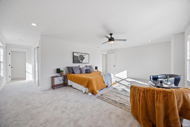 bedroom with light carpet, multiple windows, and ceiling fan