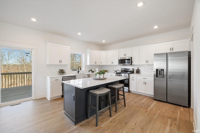 kitchen featuring white cabinetry, a center island, sink, stainless steel appliances, and a breakfast bar area