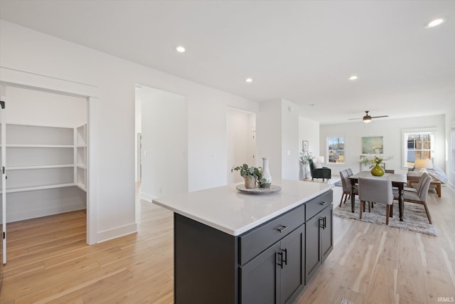 kitchen featuring ceiling fan, a center island, and light hardwood / wood-style floors