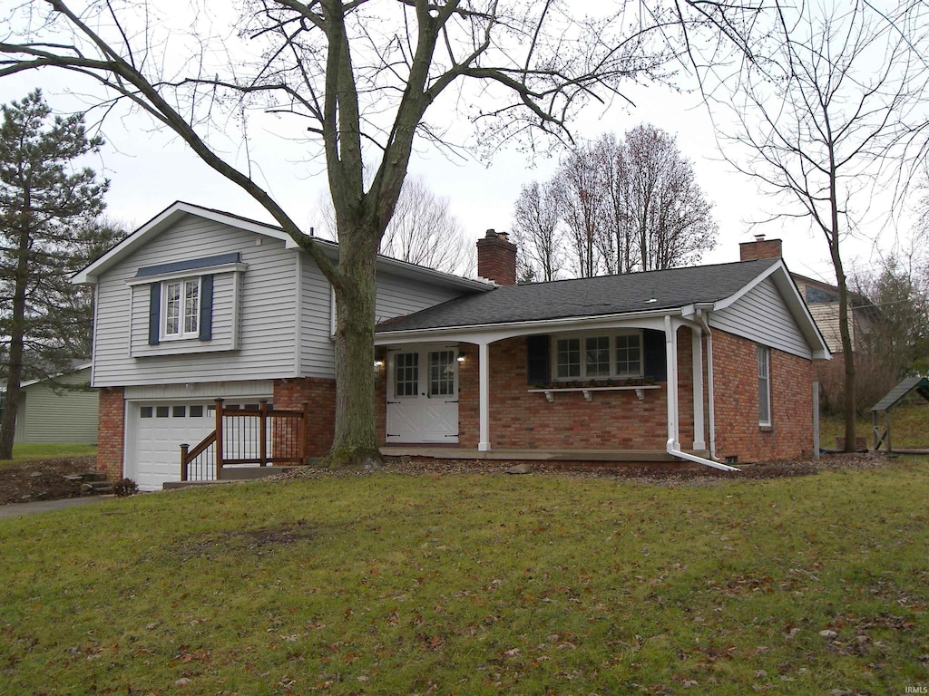 tri-level home featuring a front lawn, a porch, and a garage