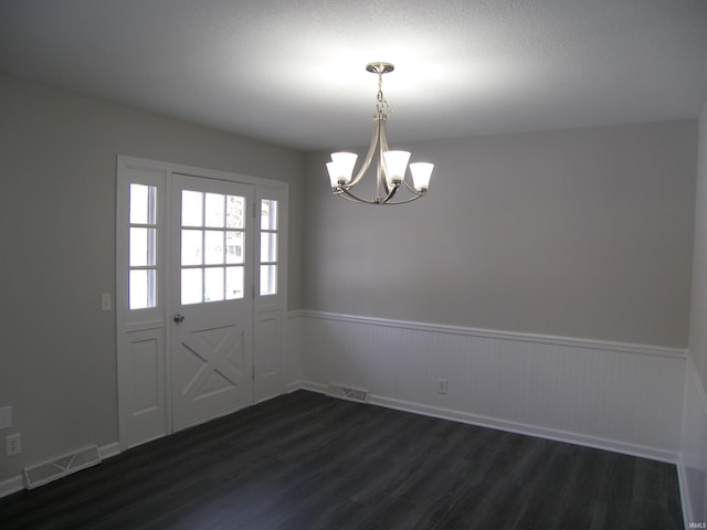 unfurnished dining area with a notable chandelier and dark hardwood / wood-style floors