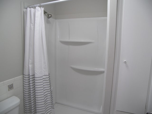 bathroom featuring toilet, tile walls, and walk in shower