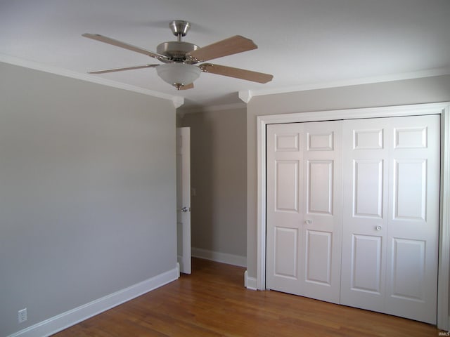 unfurnished bedroom featuring wood-type flooring, a closet, ornamental molding, and ceiling fan