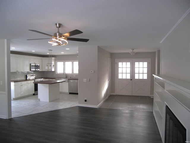 kitchen with appliances with stainless steel finishes, tasteful backsplash, a kitchen island, sink, and white cabinetry