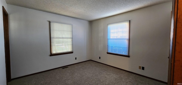 carpeted spare room with a textured ceiling