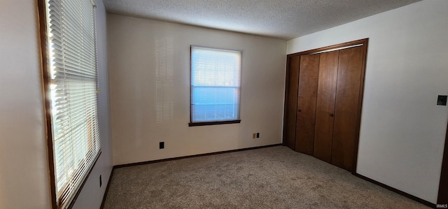 unfurnished bedroom with a textured ceiling, light carpet, and a closet