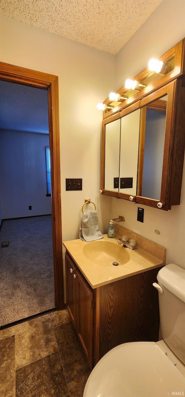 bathroom featuring a textured ceiling, vanity, and toilet