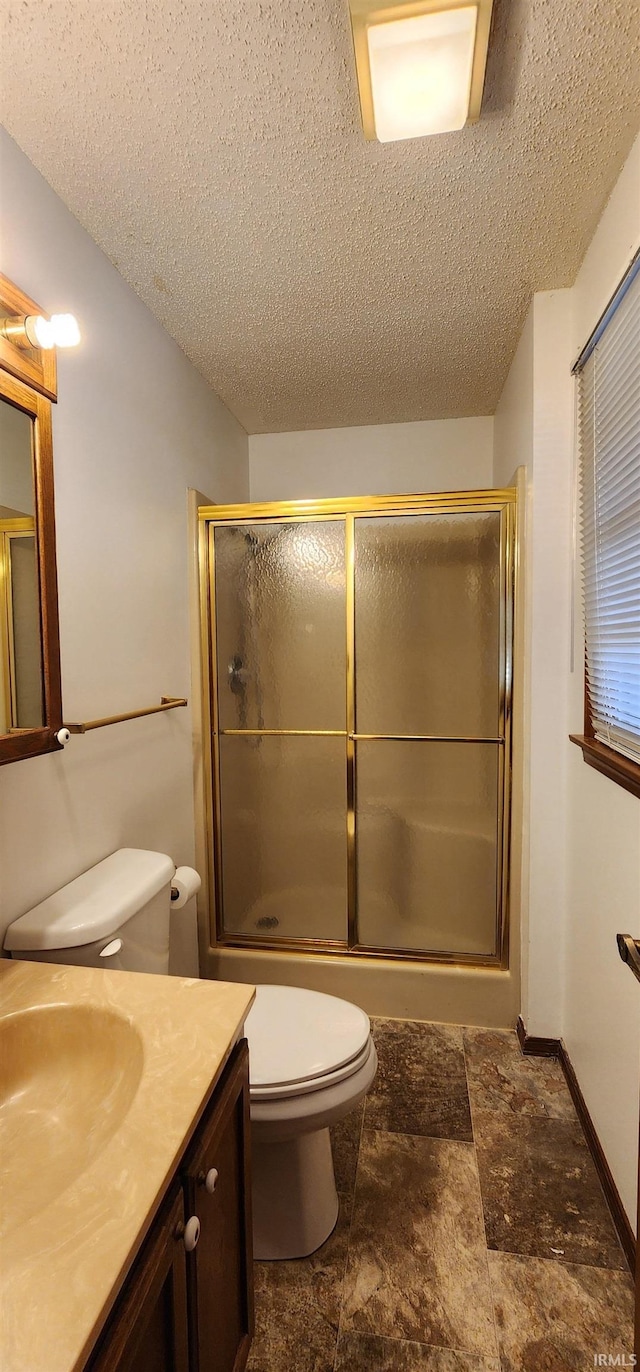 bathroom featuring a textured ceiling, vanity, toilet, and an enclosed shower