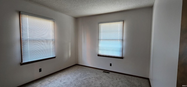 carpeted spare room featuring a textured ceiling