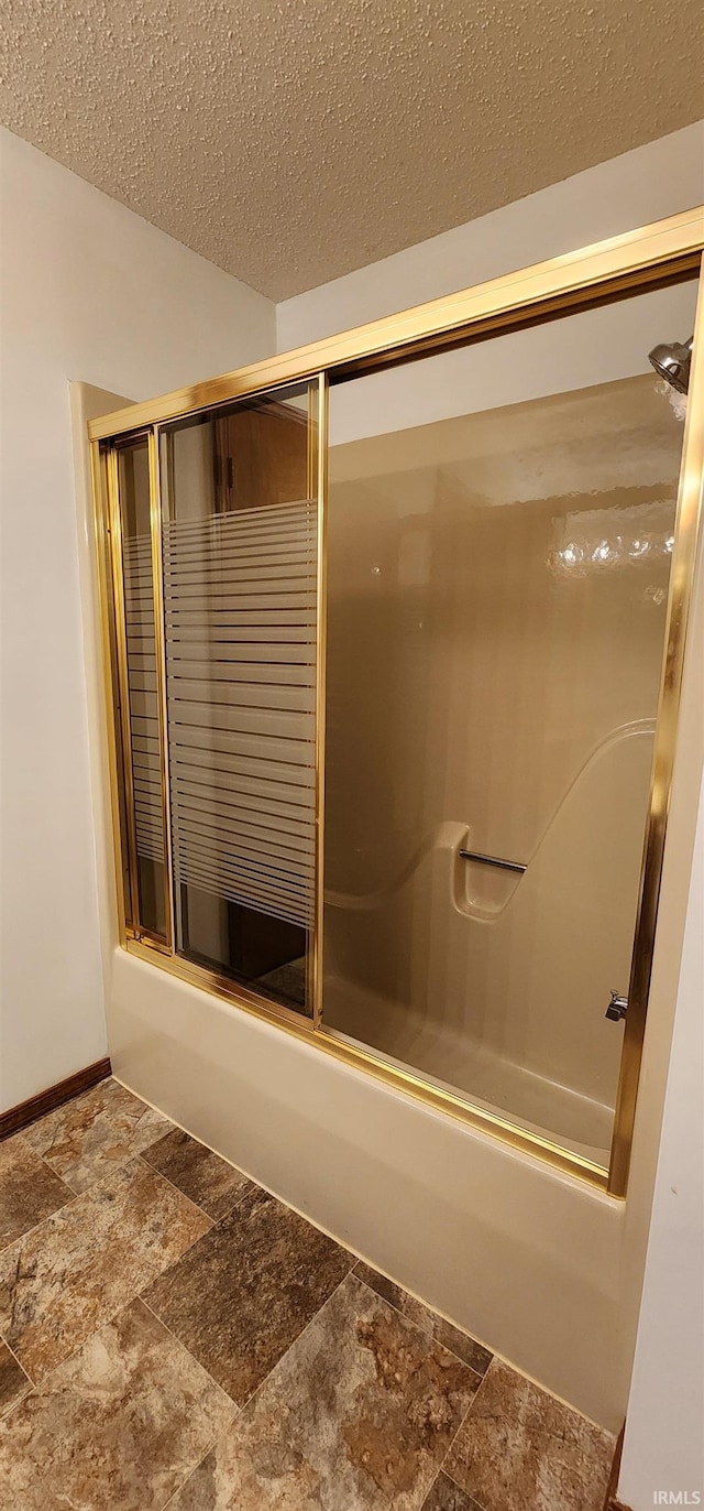 bathroom with a textured ceiling and enclosed tub / shower combo