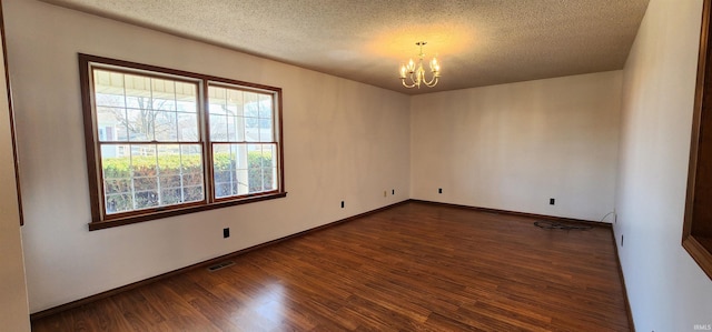 unfurnished room featuring dark wood-type flooring, a textured ceiling, and an inviting chandelier