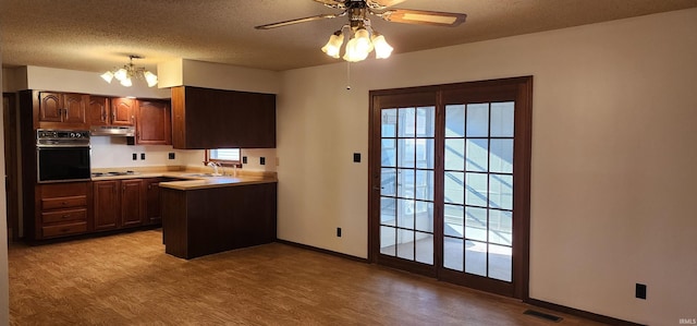 kitchen with sink, light hardwood / wood-style flooring, a textured ceiling, black oven, and ceiling fan with notable chandelier