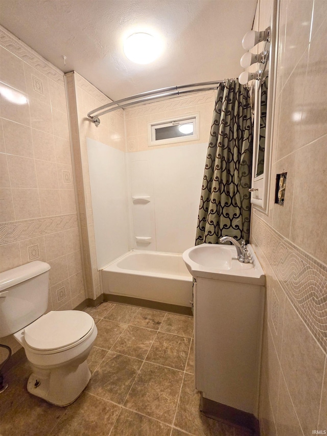 full bathroom with vanity, toilet, a textured ceiling, tile walls, and shower / tub combo with curtain