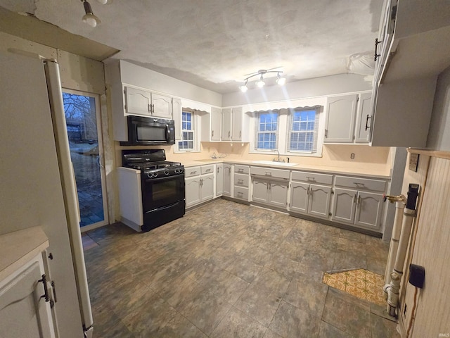 kitchen with black appliances, white cabinets, and sink