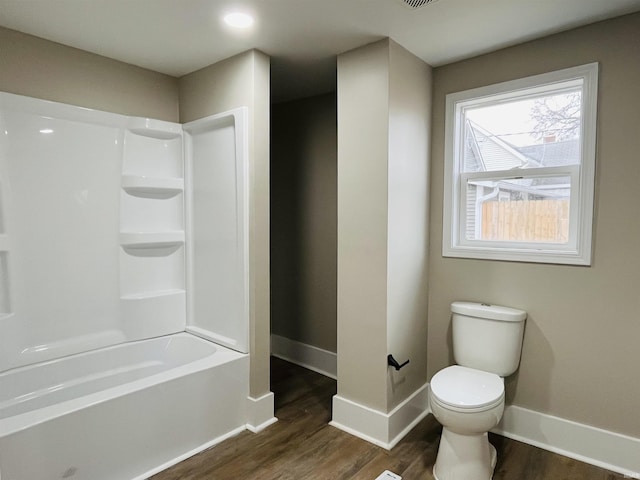 bathroom with shower / bathing tub combination, hardwood / wood-style floors, and toilet