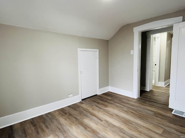 unfurnished room featuring hardwood / wood-style flooring and lofted ceiling