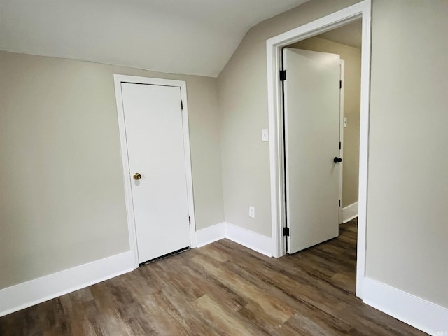 spare room with hardwood / wood-style floors and vaulted ceiling