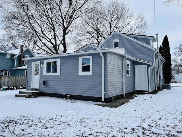 snow covered back of property featuring central AC