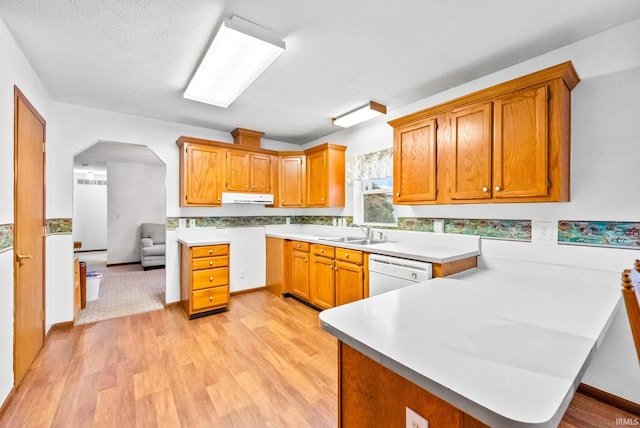 kitchen featuring dishwasher, ventilation hood, sink, light hardwood / wood-style floors, and kitchen peninsula